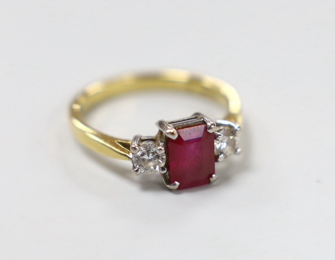 A modern 18ct gold, ruby and diamond set three stone ring, size M/N, gross weight 3.8 grams.
